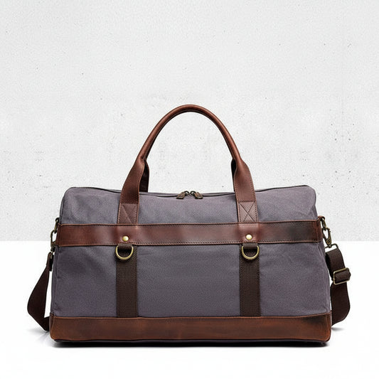 Dark-grey duffel bag with brown leather straps on a light gray background