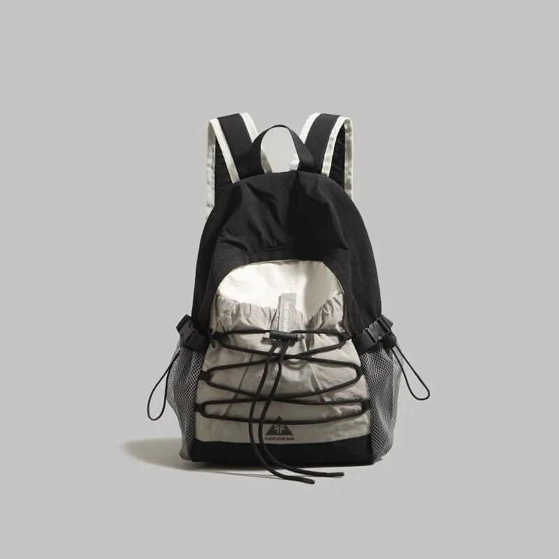 A black and light gray backpack with black laces threaded through the front, shown against a solid gray background.