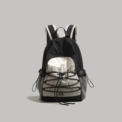 A black and light gray backpack with black laces threaded through the front, shown against a solid gray background.