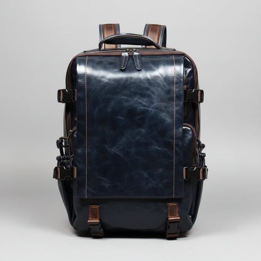 A dark navy blue distressed leather backpack with brown leather accents, zippers, and straps, shown from the back on a wooden surface against a textured brown background.