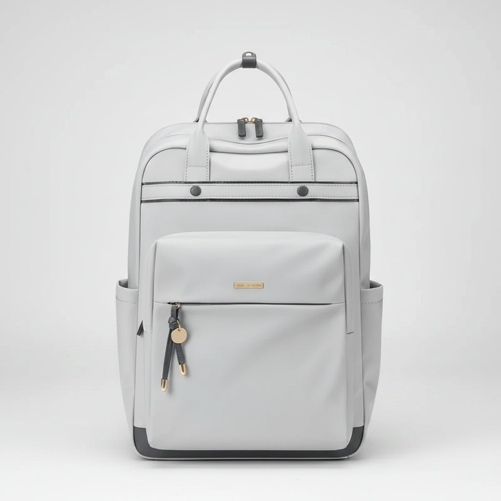 A light gray backpack with dual top handles, a front zippered pocket, side pockets, and small gold-tone hardware details, shown against a plain white background.