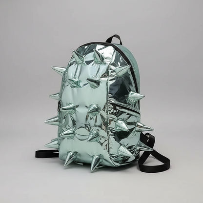A metallic silver backpack covered in sharp spikes, resting on a book on a gray staircase.