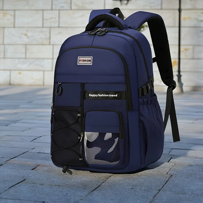 A navy blue backpack with black straps and trim, featuring a front zippered pocket with a gray and black camouflage mesh window, set on a paved stone surface against a light stone wall background.