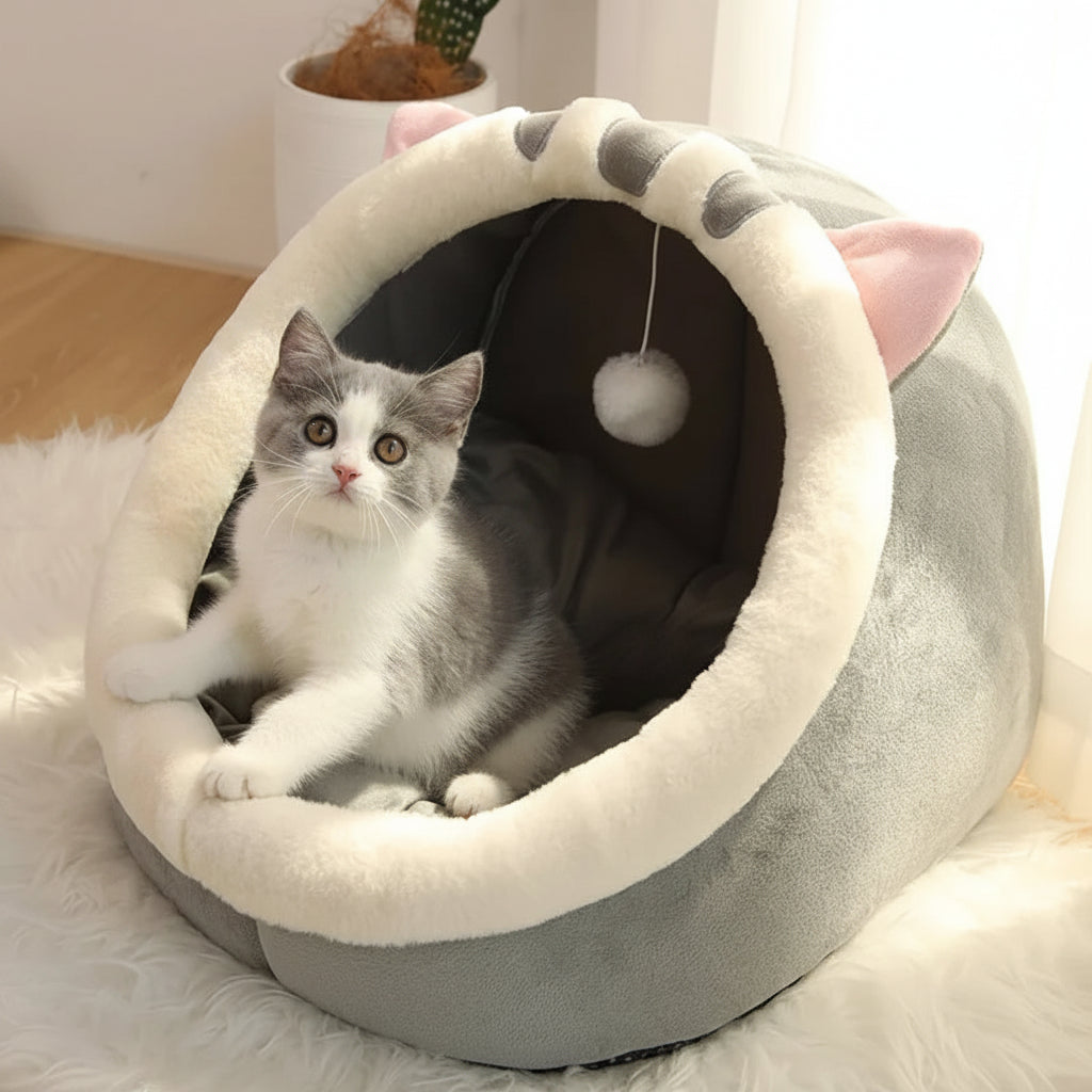 Cat lying in a gray pet bed with pink accents on a soft surface.