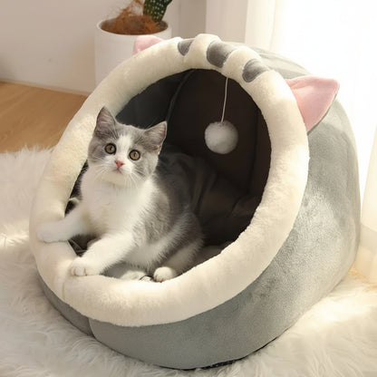 Cat lying in a gray pet bed with pink accents on a soft surface.