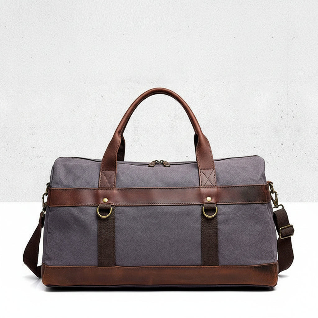 Dark-grey duffel bag with brown leather straps on a light gray background