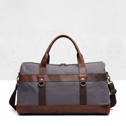 Dark-grey duffel bag with brown leather straps on a light gray background