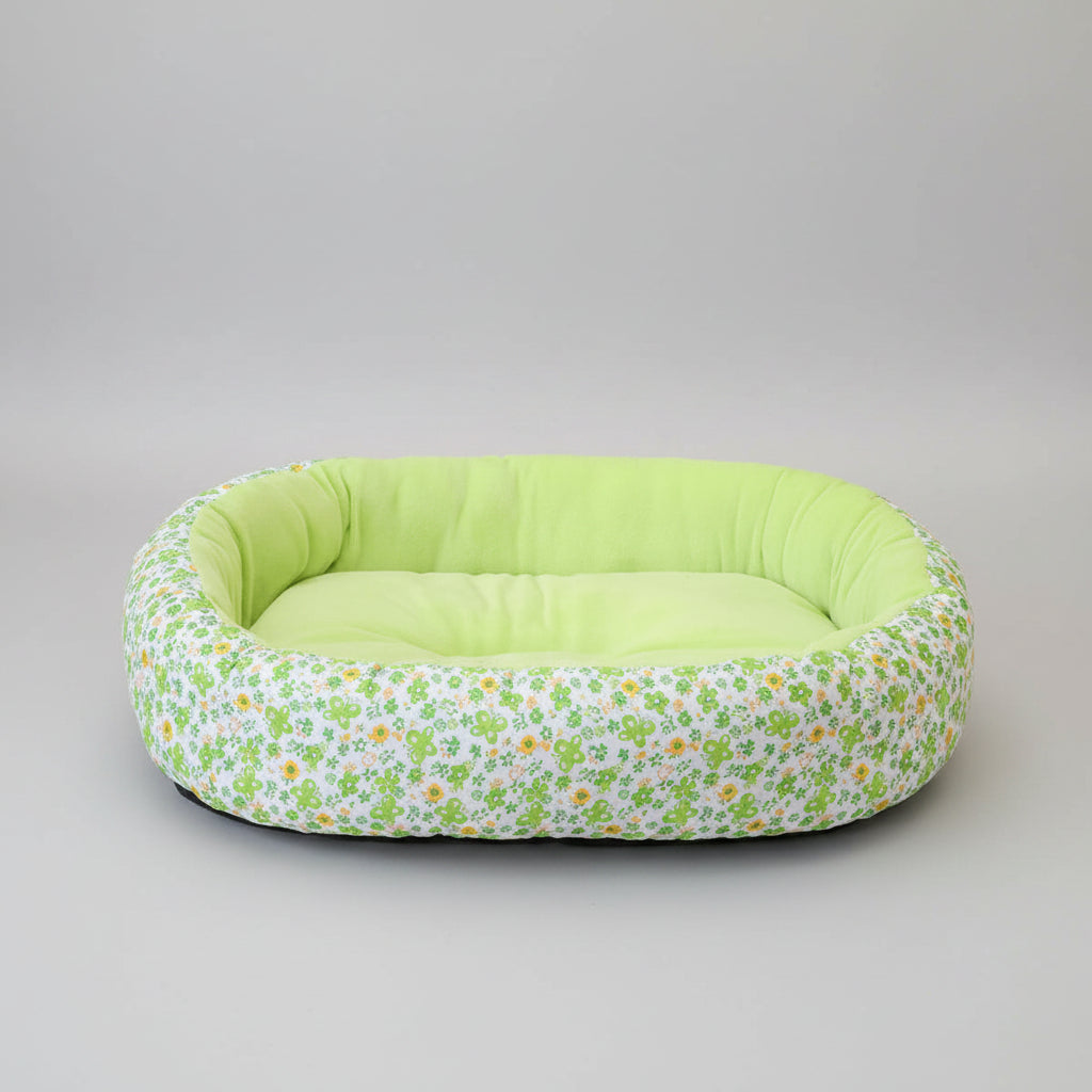 Floral-patterned pet bed with green interior on a pink rug