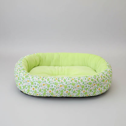 Floral-patterned pet bed with green interior on a pink rug