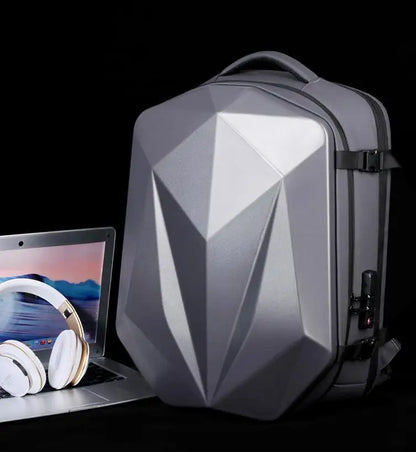 Gray geometric-patterned backpack next to a laptop and headphones on a black background
