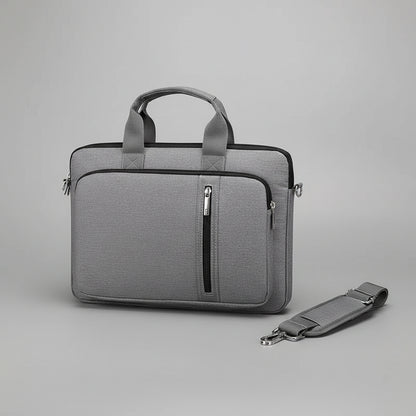 Gray laptop bag with handle and shoulder strap on a gray surface with a laptop.