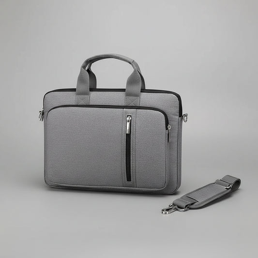 Gray laptop bag with handle and shoulder strap on a gray surface with a laptop.
