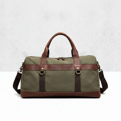 Green duffel bag with brown leather straps on a light gray background