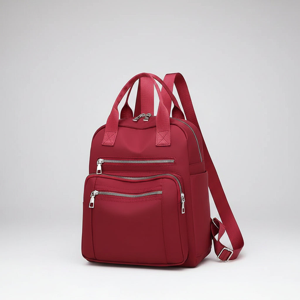 Red backpack with multiple zippers on a white background
