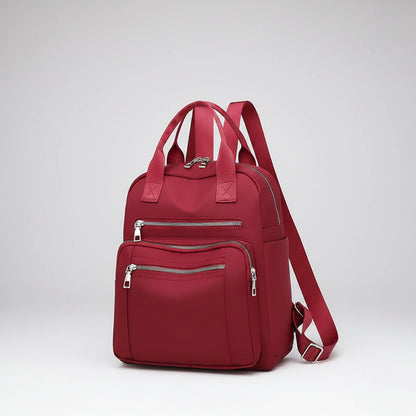 Red backpack with multiple zippers on a white background