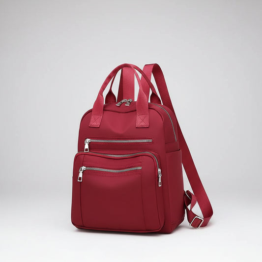 Red backpack with multiple zippers on a white background