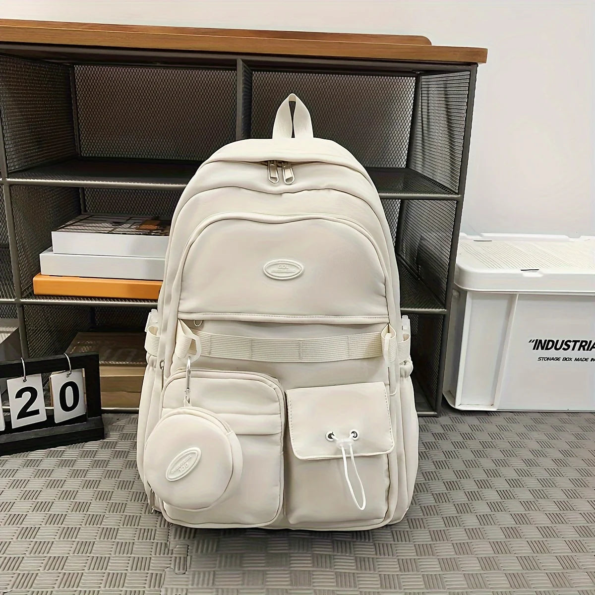 White backpack on a checkered floor with a bookshelf in the background